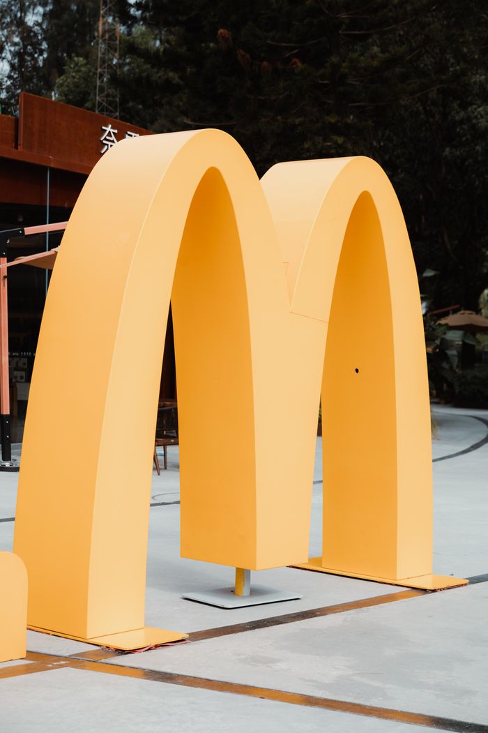 Close-up of a large yellow McDonalds arch in an outdoor setting, symbolizing fast food culture.