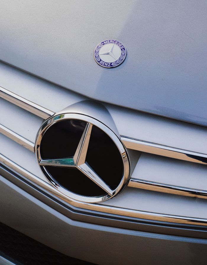 Detailed shot of a luxury cars front grille with emblem, showcasing design elegance.